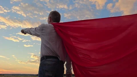 Superhero man Red Cape Blowing in Wind Walks looking into sunset, ready to save Stock Footage 307725970