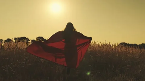 Superhero runs across the field in a red cloak fluttering in the wind at sunset Stock Footage 162131043
