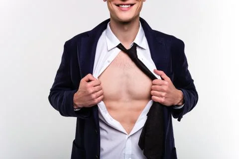 Like a superman. Part of handsome young man pulling his shirt on his chest with  Stock Photos