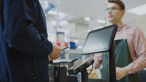 At the Supermarket: Checkout Counter Customer Pays with Smartphone for His Food Stock Footage 94330143
