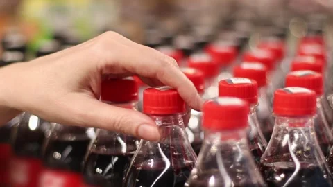 At Supermarket - Rows of Plastic Bottles with Drinks and Woman Hand Buyer Takes Stock Footage 274038660