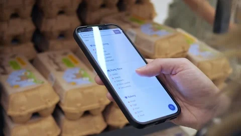 In a supermarket, a shoppers hands cross-reference a phone with products on the Stock Footage 315558272
