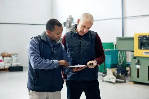 Supervising operations has never been easier. Shot of two factory managers doing Stock Photos