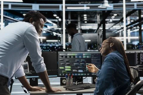 Supervisor checking work done by engineer programming in server hub Stockfoto's