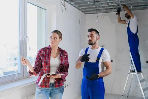 The supervisor checks the work of the builders in the apartment and writes a Stock Photos