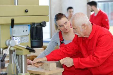 Supervisor demonstrating using file to female apprentice Stock Photos