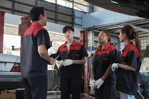 Supervisor engineer discusses with mechanic worker teams at car garage. Stock Photos