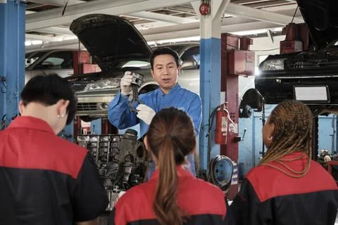 Supervisor engineer is teaching mechanic workers about car engines at a garage. Fotos de archivo