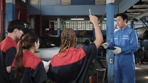 Supervisor engineer is teaching mechanic workers about car engines at a garage. Foto stock
