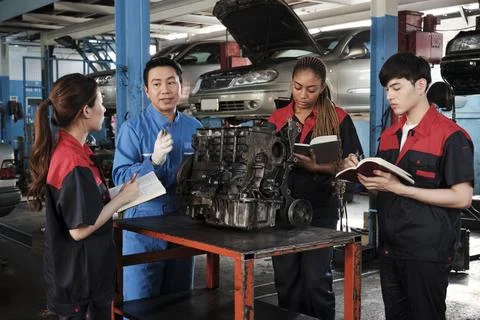 Supervisor engineer is teaching mechanic workers about car engines at a garage. Foto stock