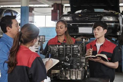 Supervisor engineer is teaching mechanic workers about car engines at a garage. 스톡 사진