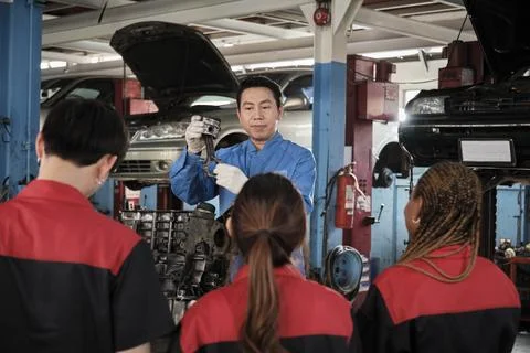 Supervisor engineer is teaching mechanic workers about car engines at a garage. 스톡 사진