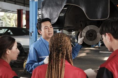 Supervisor engineer is teaching mechanic workers about car repair at a garage. Foto stock