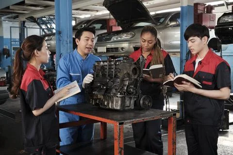 Supervisor engineer is teaching mechanic workers about car engines at a garage. Foto stock