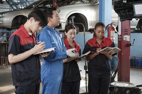 A supervisor engineer is training mechanic workers about car repair at a garage. Foto stock