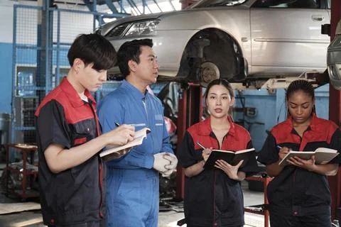 A supervisor engineer is training mechanic workers about car repair at a garage. Foto stock