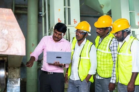 Supervisor explaining about machinery or debugging using laptop while in fron Stock Photos