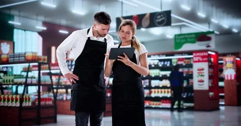 Supervisor Guides New Workers Through Training At Busy Supermarket 스톡 사진