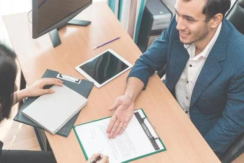 Supervisor of Human resource is inviting new employee to sign work contract Stock Photos
