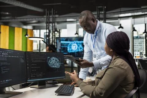 Supervisor overseeing intern using computer in workplace to do maintenance Stock Photos