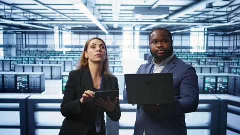 Supervisor in server farm overseeing engineer fixing network issues Stock Footage 277656780