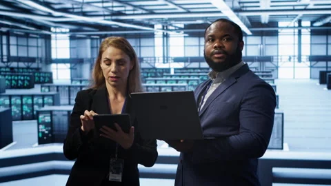 Supervisor in server farm overseeing engineer fixing network issues Stockbeeldmateriaal 277658493