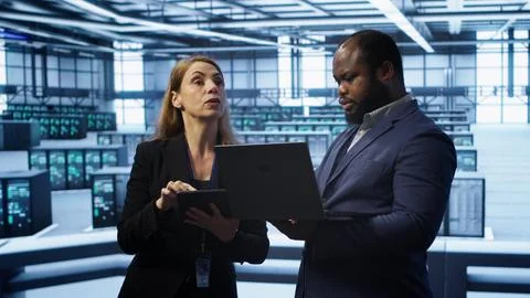 Supervisor in server farm overseeing engineer fixing network issues 스톡 사진