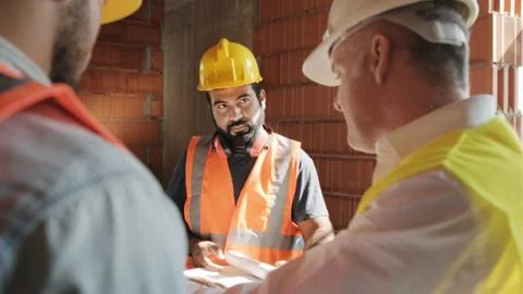 Supervisor Showing Building Plans To Workers In New House Foto stock