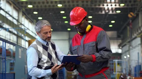 Supervisor Signing a Document in a Factory and Talking to Black Worker Stock Footage 283386170