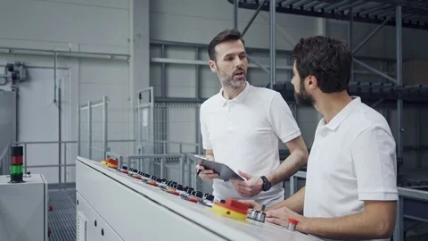 Supervisor teaching new employee machine operating controls in factory Stock Footage 108446570