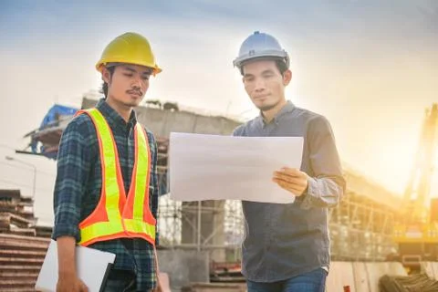 Supervisor use blueprint talking with Foreman Construction site background ar Stock Photos