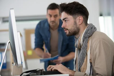 Supervisor watching young man using computer Stock Photos