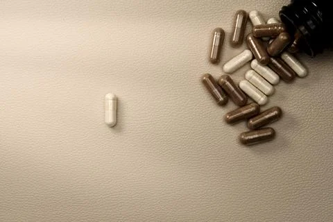Supplements capsules spilling from bottle representing healthcare Stock Photos