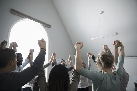 Support group holding hands overhead in circle, in support Stock Photos