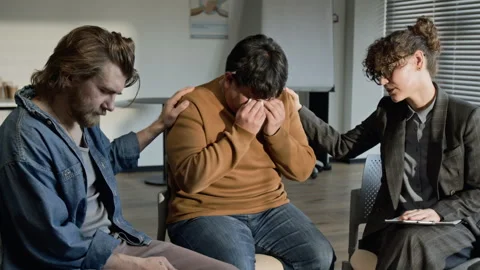 Support Group Members Comforting Crying Asian Man in Therapy Stock Footage 337241162