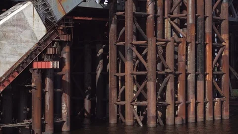 The support of a not built bridge from rusty metal structures on the river. Video stock 91788599