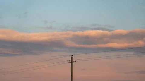 The support of power lines against the background of an orange sunset sky Stock Photos