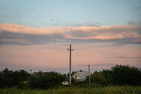 The support of power lines against the background of an orange sunset sky Stock Photos