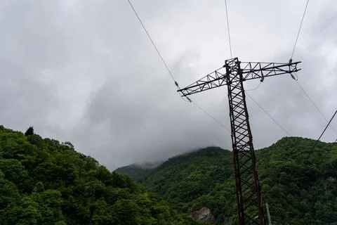 Support of power lines against the background of mountains and thick clouds Stock Photos