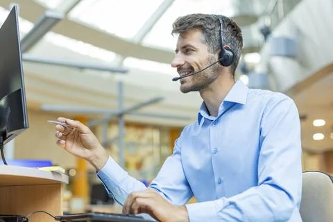 Support service operator talking to customer sitting at desk wearing headse.. Stock Photos