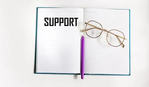 The support text is written on a notepad with a pen and glasses Stock Photos