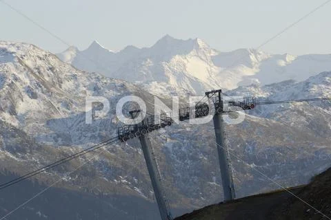 Supporting Poles With The Ropes Of A Cable Car, In Front Of Snow-Covered Moun