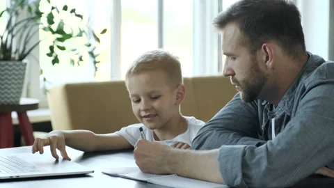 Supporting Son In His Studying. Side View Of Cheerful Young Father Helping Stock Footage 157814617