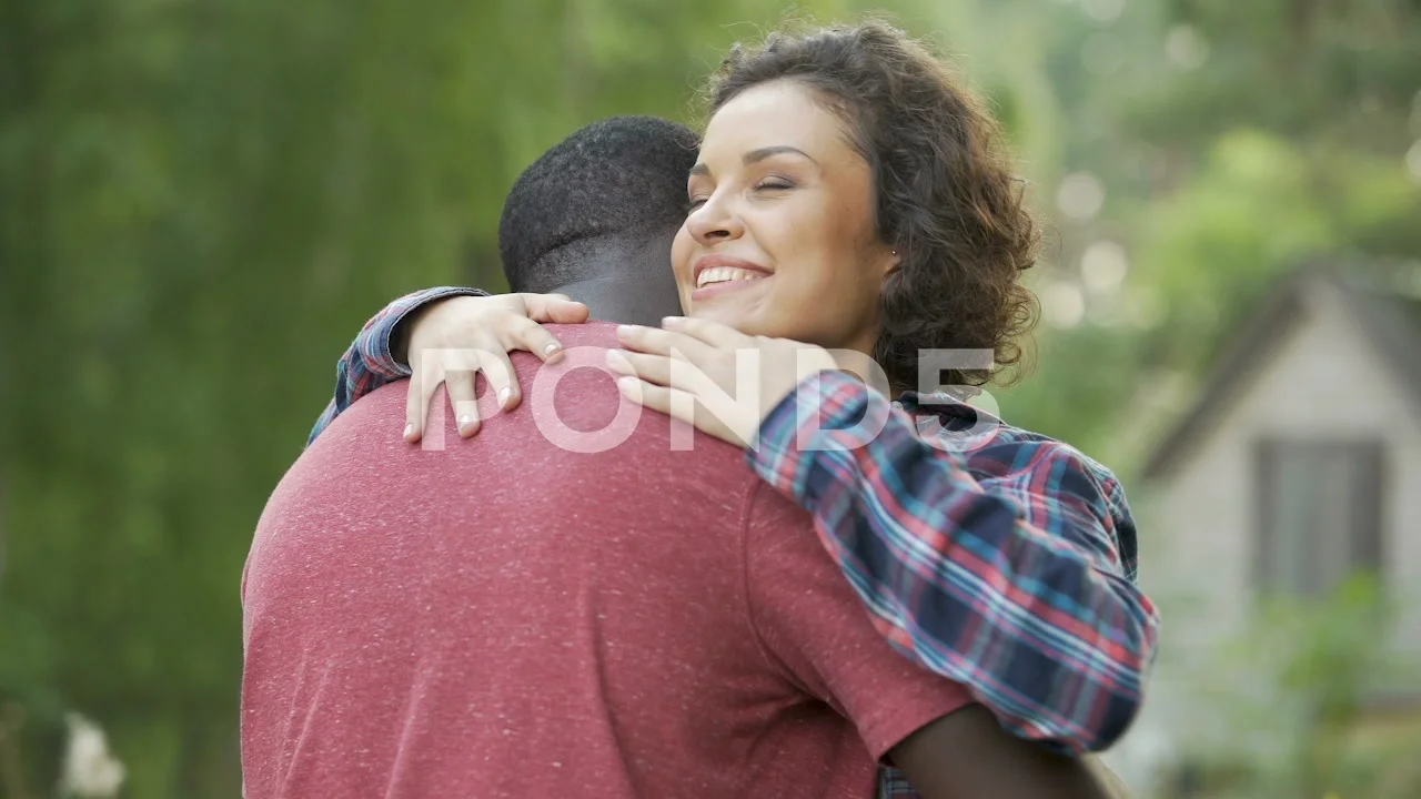 Supporting wife meets husband in front of home and gives him a welcome hug