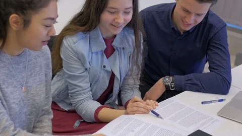 Supportive girl explaining to her classmates in the classroom Stock Footage 74612544