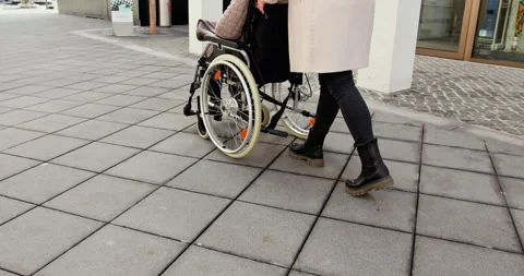Supportive Mobility A Person Gently Assisting Someone in a Wheelchair on a Stock Footage 290172930