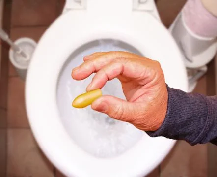 Suppository for constipation in the hand of an elderly person in the toilet a Stock Photos