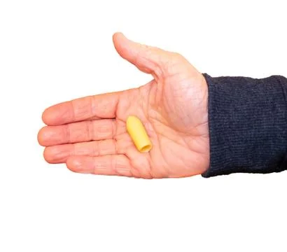 Suppository for constipation in the hand of an elderly person against the whi Stock Photos