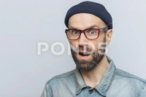 Suprised terrified unshaven male stares at camera and keeps mouth widely open Stock Photos