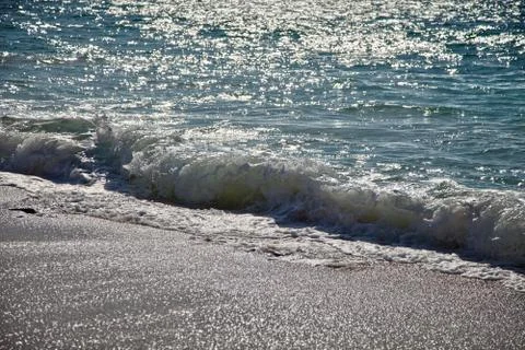 Surf breaking on the sandy beach Stock Photos